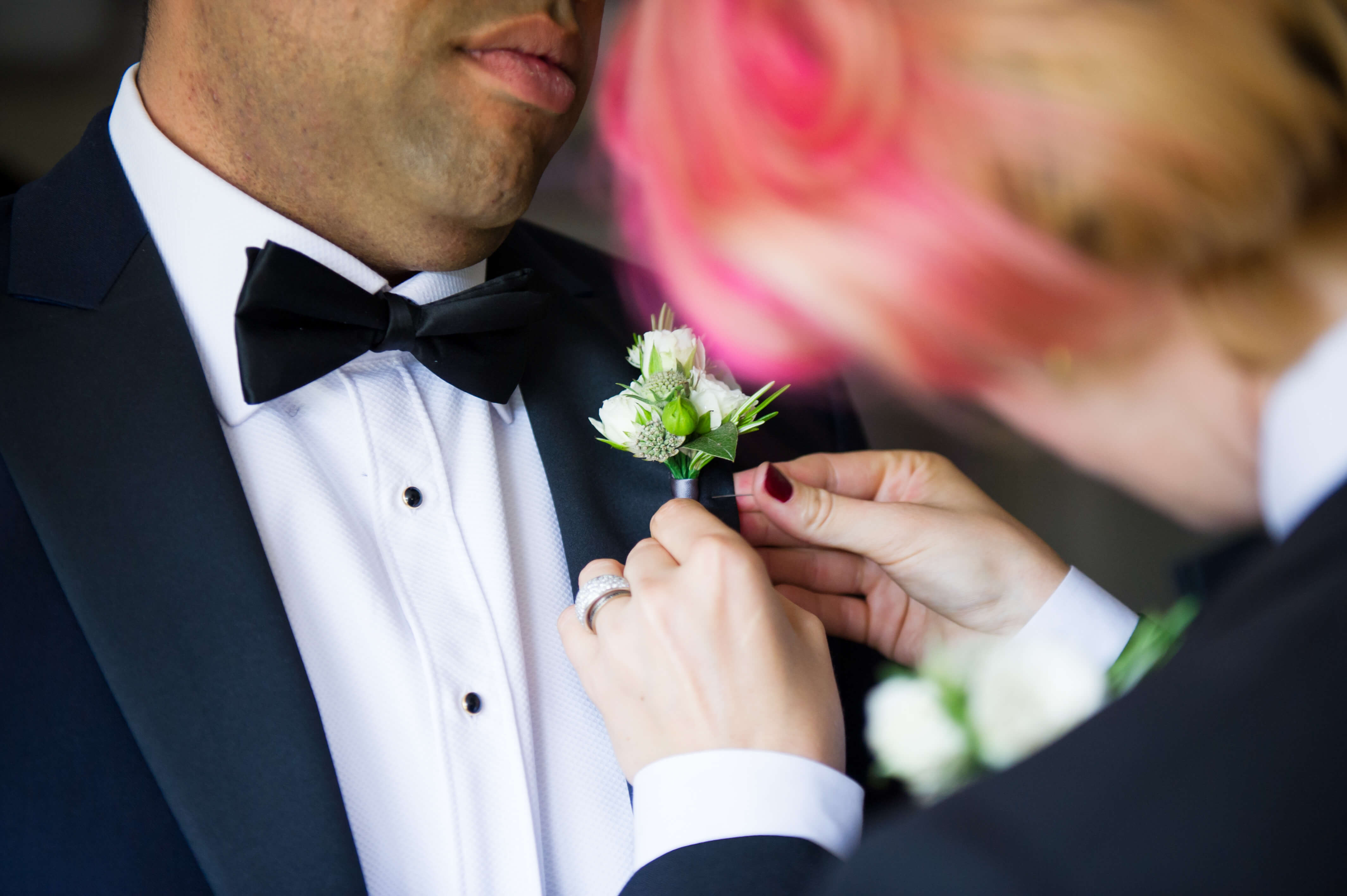 securing a button hole wearing tuxedos at voewood wedding in norfolk